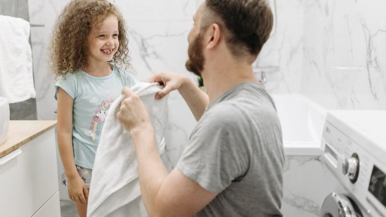 A father and daughter enjoying a joyful moment in a bright, modern bathroom.