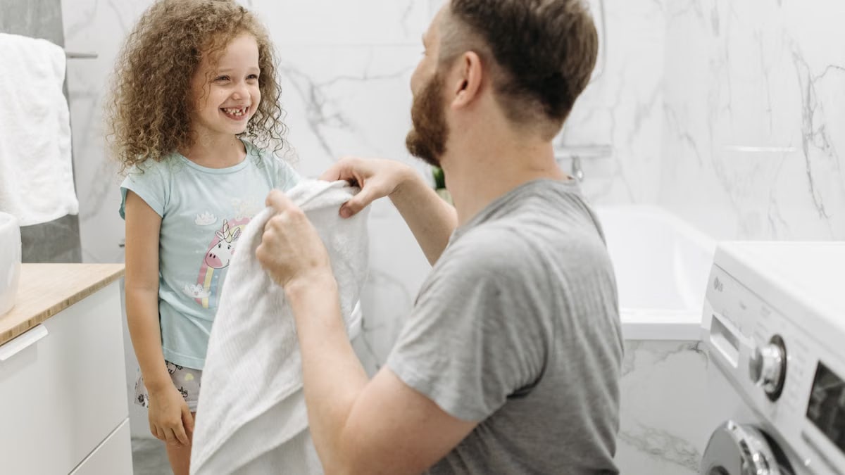 A father and daughter enjoying a joyful moment in a bright, modern bathroom.